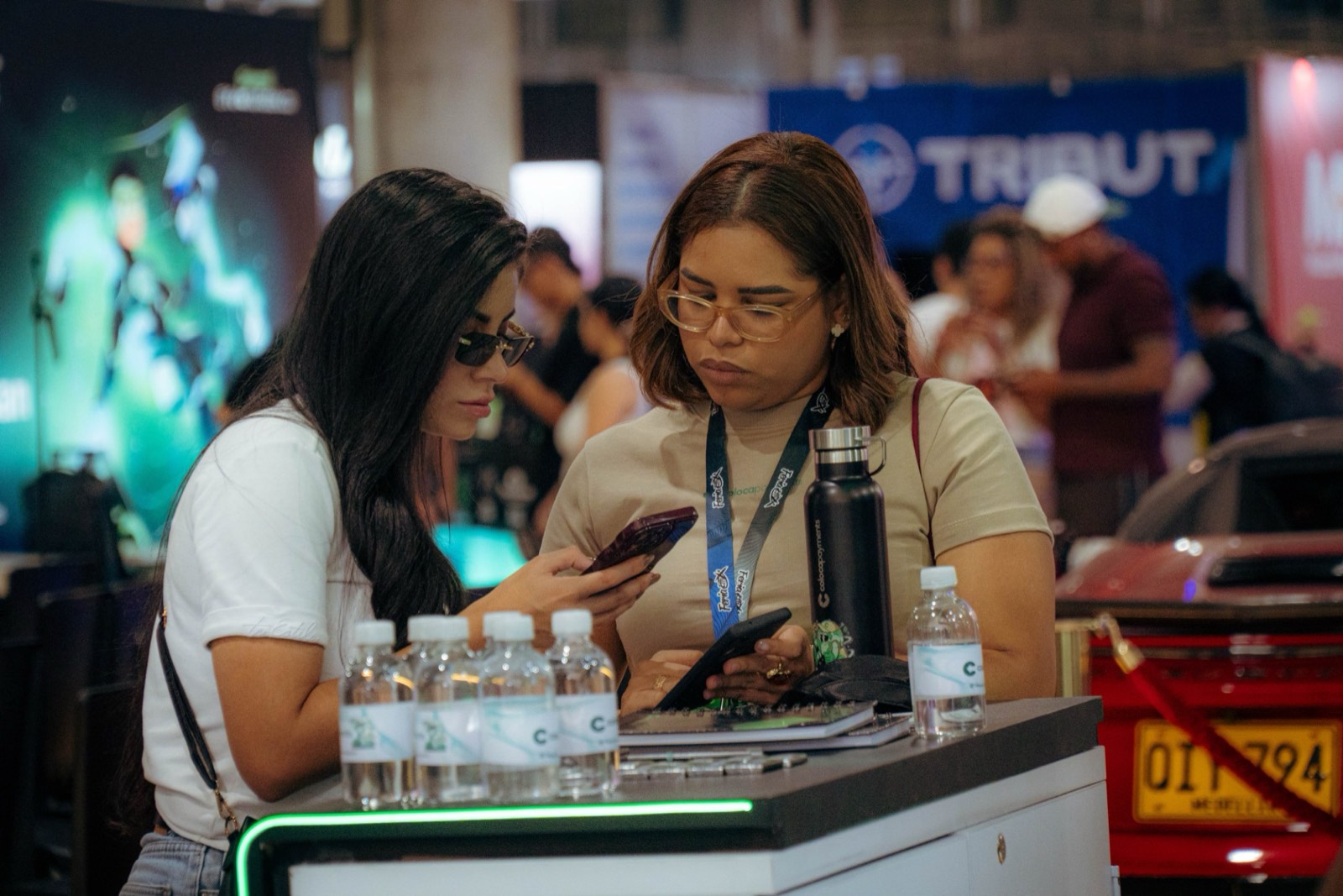 Two people look at their phones at the Coloca booth counter during EFFIX 2026